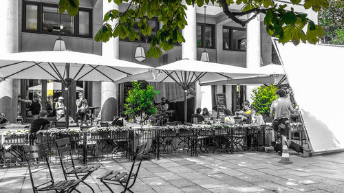 Chairs and tables at sidewalk cafe amidst buildings in city