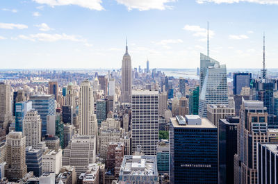 Aerial view of buildings in city against cloudy sky