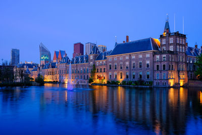 Buildings by river against clear sky