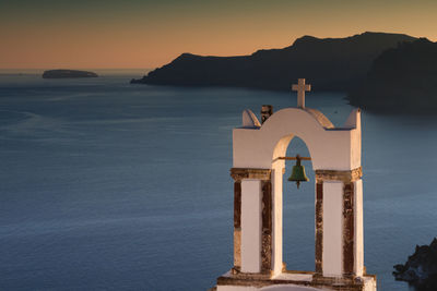 Bell tower against sea during sunset