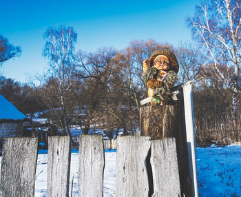Man standing by wooden post during winter against sky