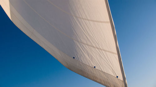 Low angle view of boat canvas against clear blue sky