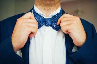 Midsection of man making face against blue wall