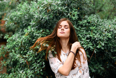 Portrait of young woman standing against plants