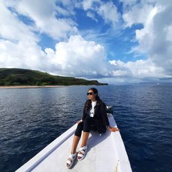 Portrait of young woman in boat on sea against sky