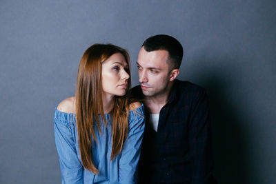 Couple sitting against gray background