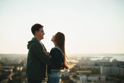 Couple embracing while standing against sky