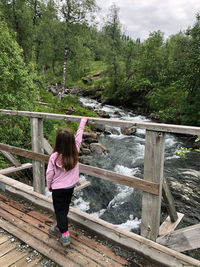 Rear view of woman standing on footbridge