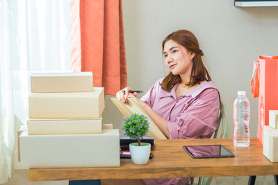 Thoughtful young woman looking away while sitting at home