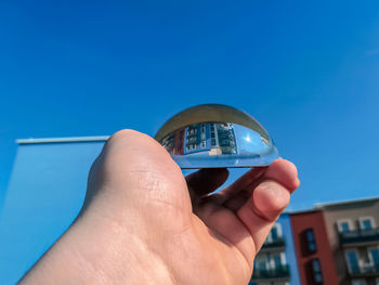 Close-up of hand holding blue against built structure