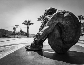 Statue by palm tree against sky