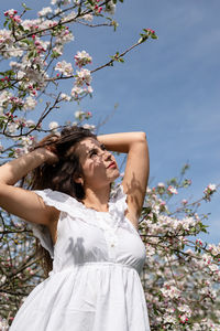 Portrait of smiling young woman standing against trees