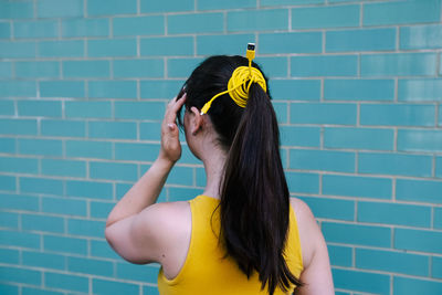 Woman ponytail tied up with cable wire in front of wall