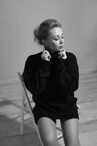 Side view of young woman sitting on floor at home