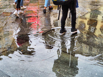 Low section of people walking on wet street