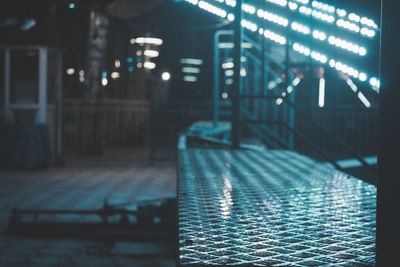 Empty illuminated footpath by buildings in city at night