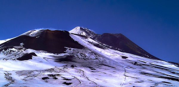 Low angle view of snowcapped mountain against clear blue sky