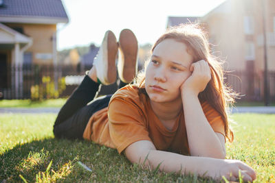 Cute girl looking away while lying on grass