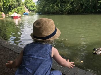 Rear view of woman sitting by river