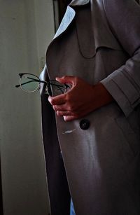 Midsection of man holding eyeglasses