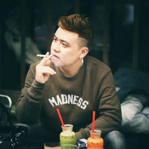 Young man looking away while sitting on table