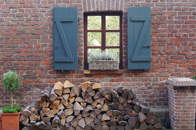 Firewood stack in back yard against brick wall house
