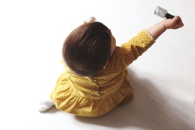 Rear view of girl sitting on table