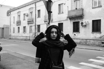 Portrait of young woman standing on road in city