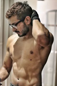 Close-up of shirtless man standing against wall