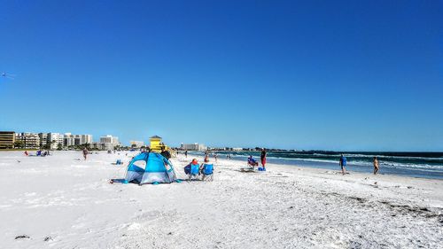 People at beach against clear sky