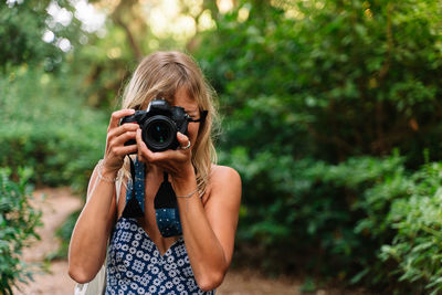 Midsection of woman photographing against plants