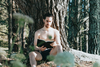 Portrait of shirtless young woman exercising in forest