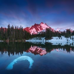 Scenic view of lake by snowcapped mountain against sky