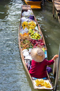 Rear view of woman selling fruits while sitting in boat