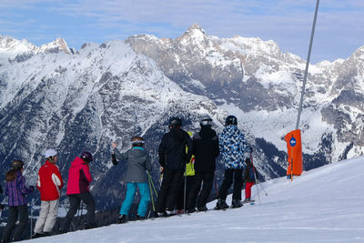 People standing on snowcapped mountain against sky