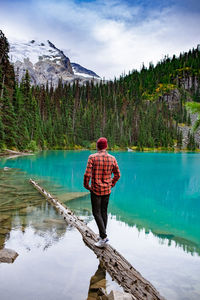 Rear view of man standing by lake against sky