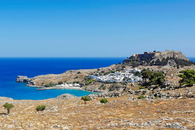 Scenic view of sea by buildings against clear blue sky