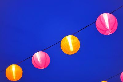 Low angle view of lanterns hanging against clear blue sky