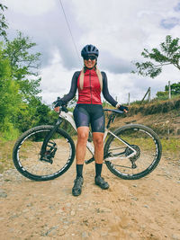 Full length portrait of woman with bicycle on land against sky