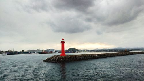 Lighthouse by sea against sky