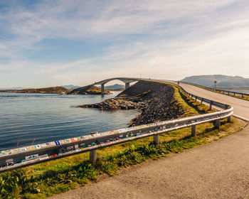 Bridge over road by sea against sky