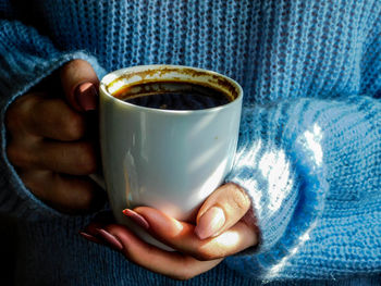 Midsection of man holding coffee cup
