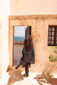 Rear view of woman standing against wall