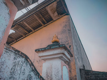 Low angle view of bird on building against sky