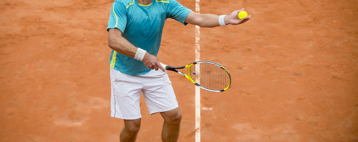 Midsection of man playing tennis