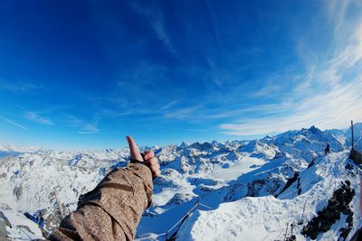 Woman on snowcapped mountain against blue sky