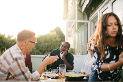 Multi-generation family talking while having lunch at table on porch