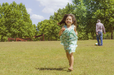 Full length of happy girl walking on grassy field