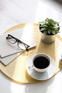 Office desk with coffee cup, succulent plant, eyeglasses and notepad. minimal style.