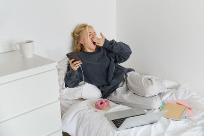 Portrait of young woman sitting on bed at home